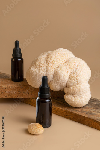 Two Bottles of dark amber glass with essential oil with beautiful lion mane mushroom on beige background © BooFamily