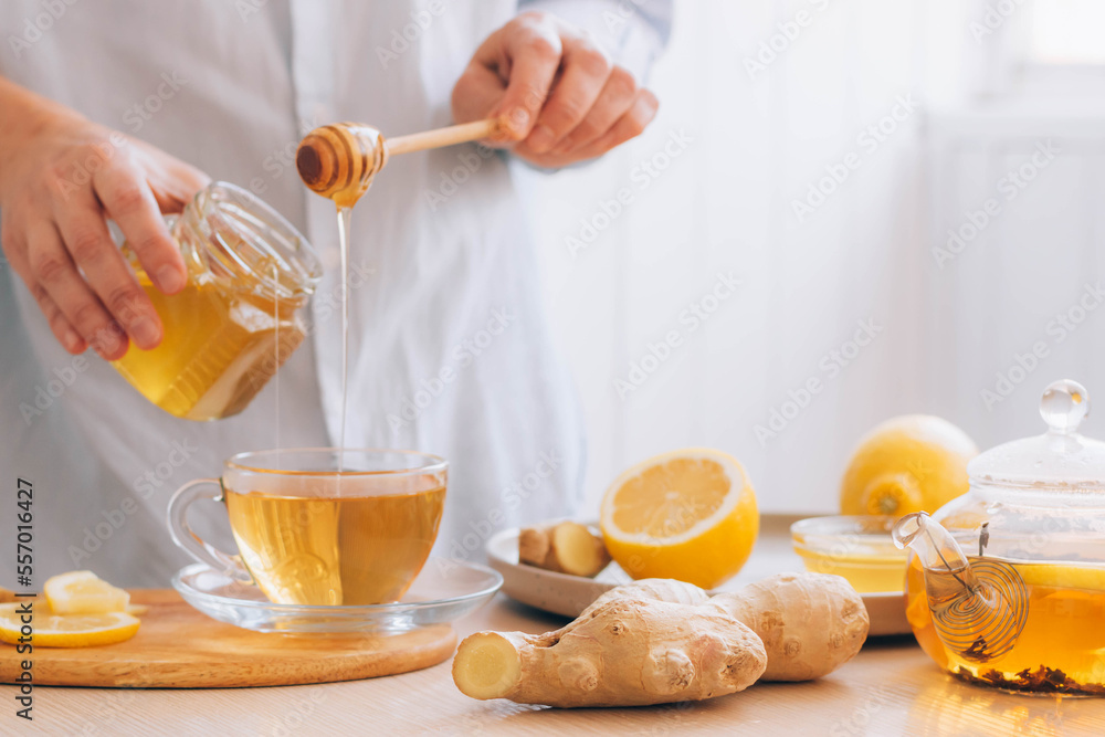 Women's hands prepare hot drink tea from ginger root lemon honey for cold treatment and prevention