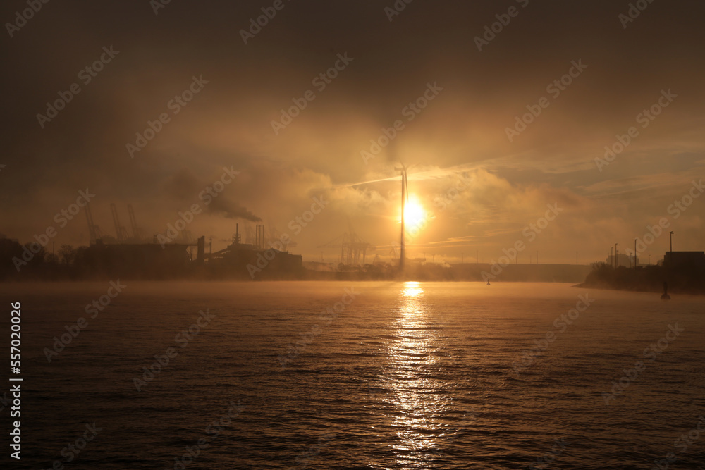 Dramatischer Sonnenaufgang über den Hamburger Hafen mit Nebel und Wolken im Winter Dramatischer Sonnenaufgang über den Hamburger Hafen mit Nebel und Wolken im Winter