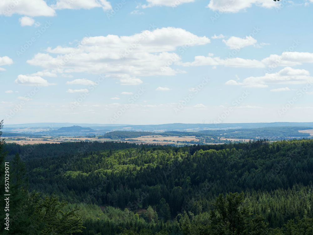 Obraz premium Landschaft in Hessen. Waldgut von Burgwald entlang Gerlachsberg und Stirnhelle-Rundweg. Blick uber den Hoherodskopf auf die Amöneburg, Lahnberge, Schloss Marburg und Windpark Marburg 