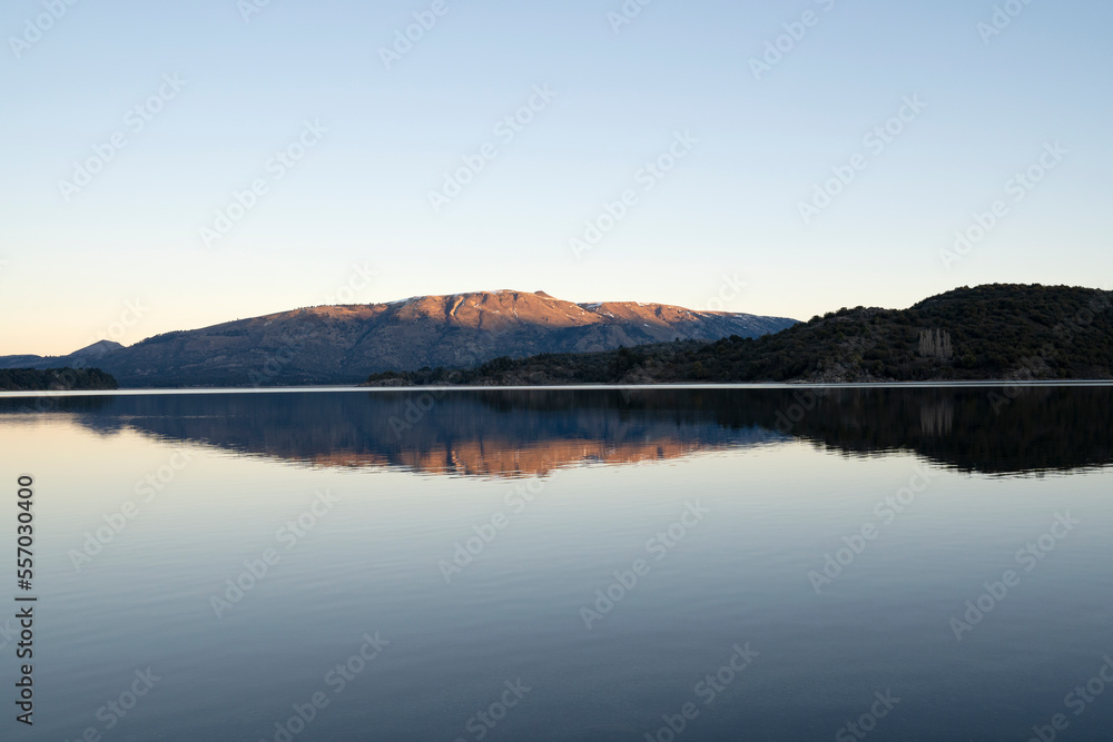 View of the calm lake and mountains at sunset. Beautiful landscape and sky reflection in the water surface. 