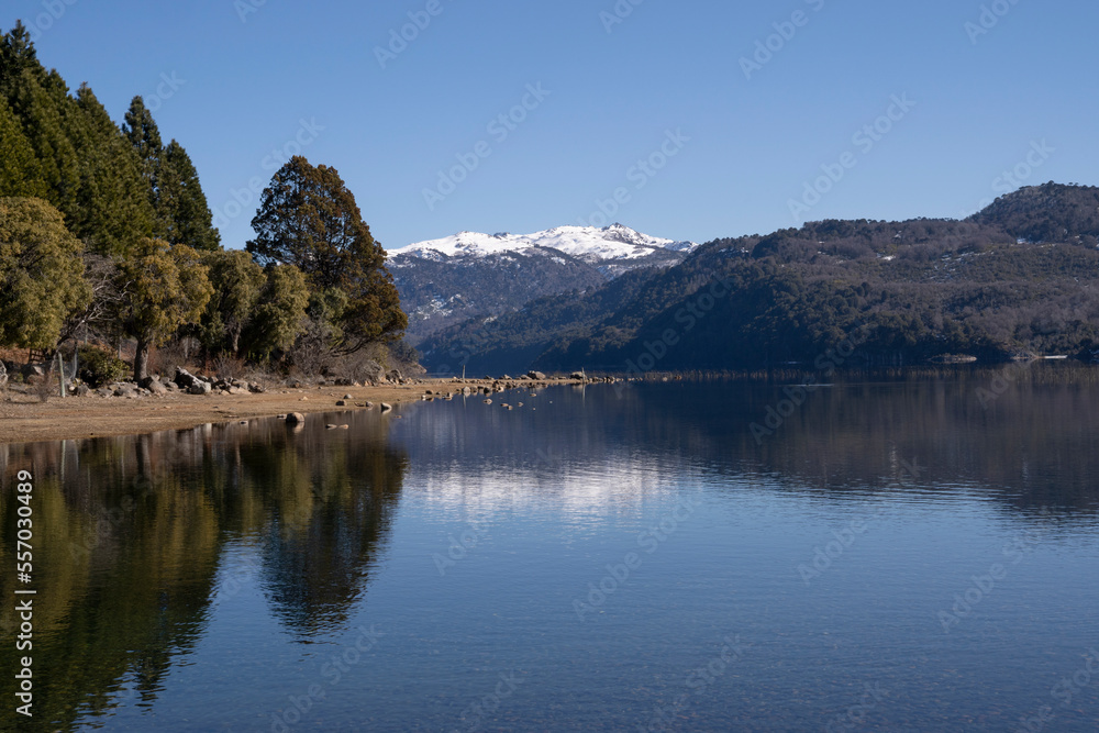 Summer day in the alps. The reflection of the blue sky, green forest and mountains in the lake's water surface.