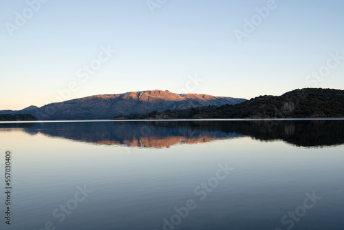 View of the calm lake and mountains at sunset. Beautiful landscape and sky reflection in the water surface. 