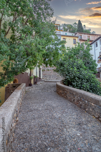 Granada, Spain, 21st of October, 2022. On the way to the Alhambra Palace. Carrera Del Darro street with small souvenir shops and walking tourists. Narrow cobbled street of Granada in sunshine. 