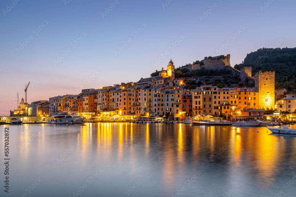 Die mittelalterliche Hafenstadt Portovenere  mit bunten Hausfassaden im Abendlicht bei spiegelnden Lichtern im Meer