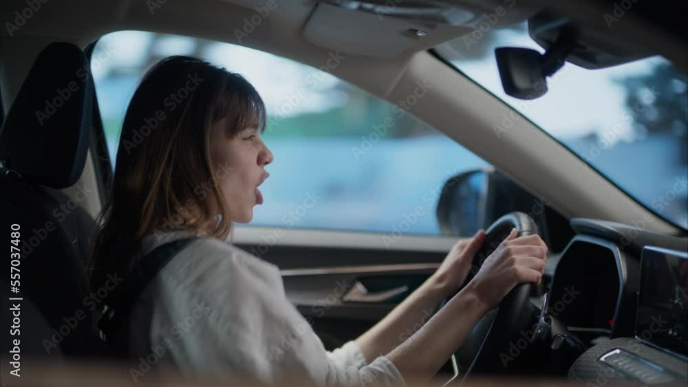 Caucasian female dancing and singing to her favorite song while driving the car during the suburbs neighborhood