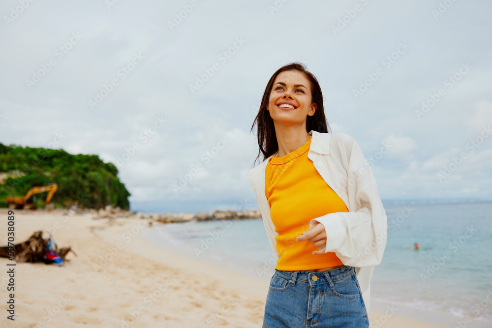 Portrait of a happy woman smile with teeth with long hair brunette walks on the sea beach summer travel and feeling of freedom, balance
