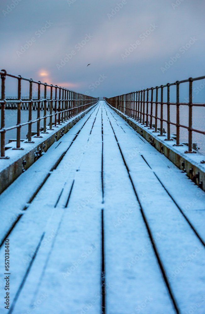 Naklejka premium A freezing, snowy morning at Blyth beach at the old wooden Pier stretching out to the North Sea