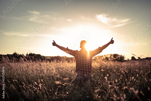 young man in a field looking up to the sky with thumbs up, enjoys life and summer, nature, happiness positivity 