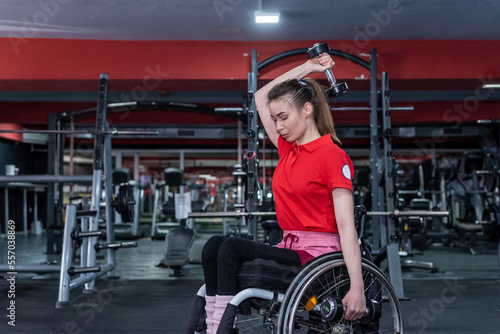 Woman in a wheelchair lifting weight in gym