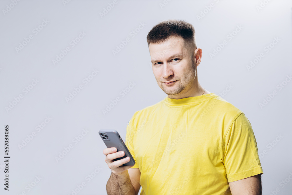 Man in yellow T-shirt holds mobile phone in his hand. Attractive guy Man in yellow T-shirt holds mobile phone in his hand. Attractive guy