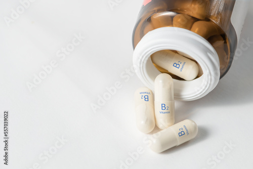 Vitamin B2. Vitamins in capsules for the production of red blood cells. White capsules with vitamin B2 or riboflavin scattered on the table from a bottle. Dietary supplements in tablets.