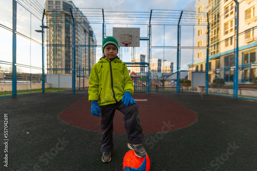 An Asian boy is playing football on the street in autumn 