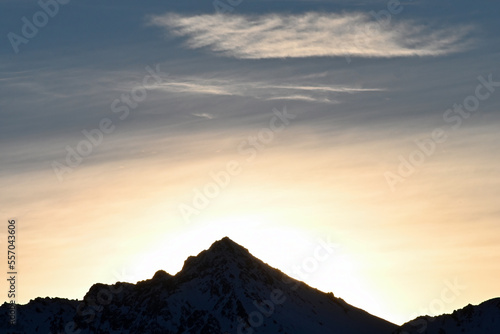 Winter sun rising behind a peak in Alaska's Chugach Range.