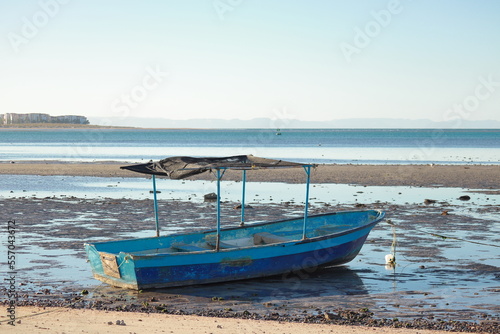 An old fishing boat, without a motor and stranded on the beach during low tide