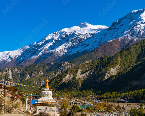 Buddhist stupa along the Annapurna Circuit Trek with white snowy peaks in the distance, Himalaya mountains, Nepal