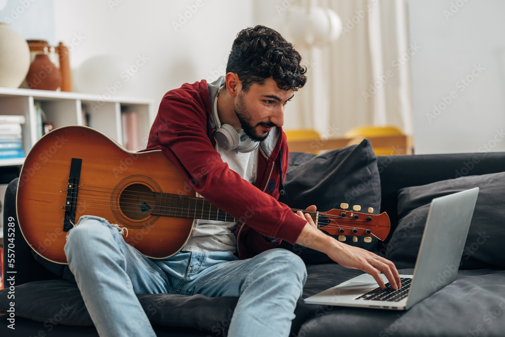 Young man practices guitar at home