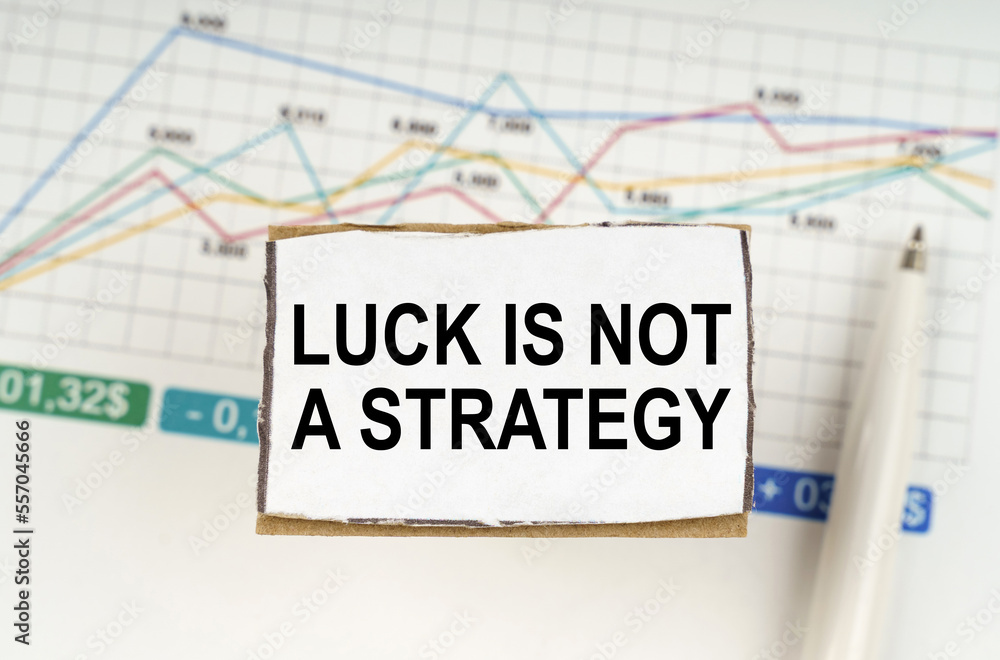 Against the background of business graphics and pens, a sign with the inscription - Luck is Not a Strategy Against the background of business graphics and pens, a sign with the inscription - Luck is Not a Strategy