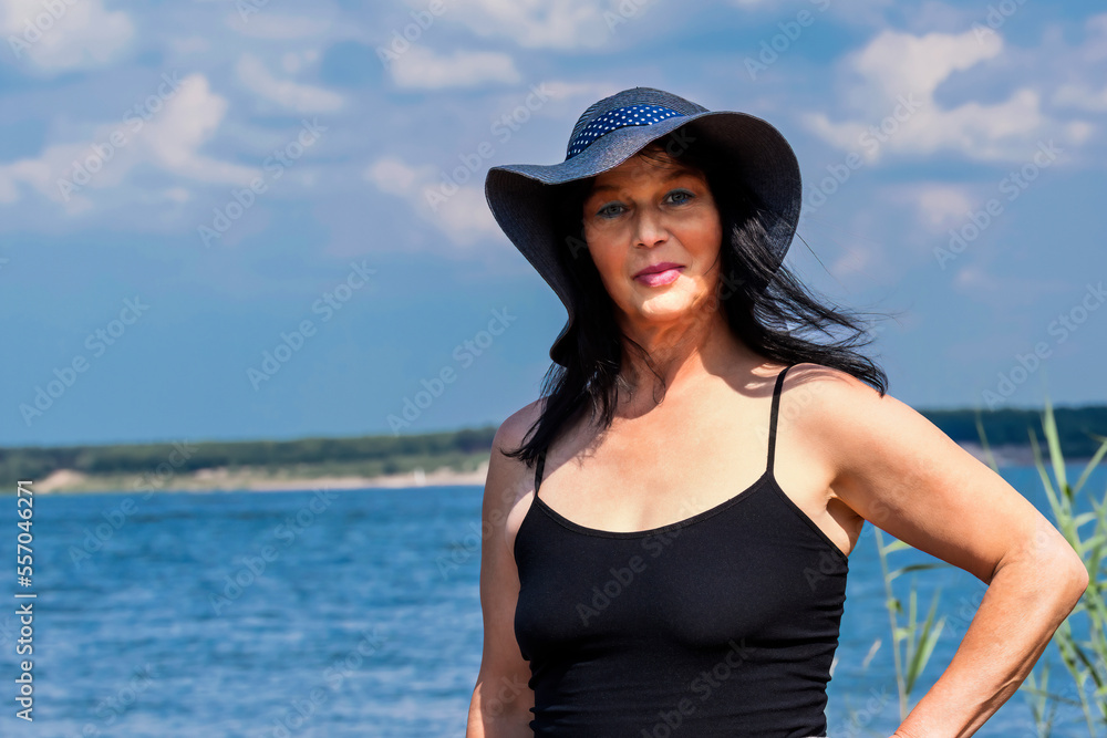 Ältere hübsche Frau mit Hut am See