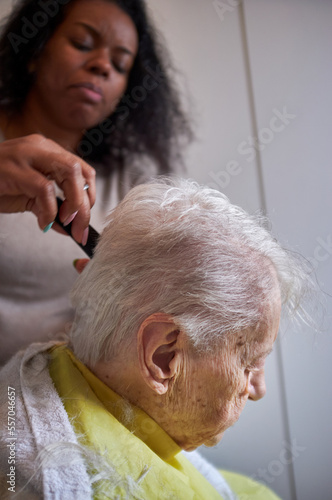 caregiver, cutting her elderly woman hair