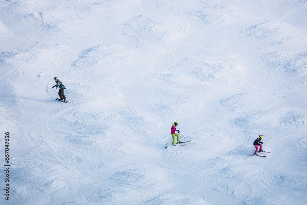 Three skiers on a mountain going down a slope in Zell am Ziller resort in Austrian Alps. 