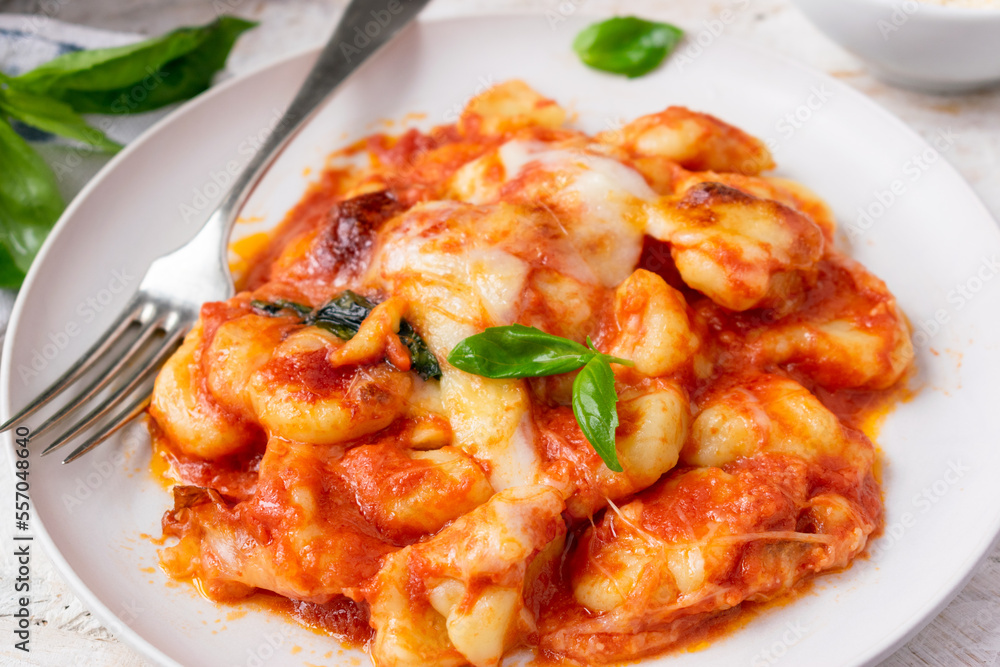 Sorrentina-style potato Gnocchi with tomato sauce, mozzarella cheese and basil on a with background Sorrentina-style potato Gnocchi with tomato sauce, mozzarella cheese and basil on a with background