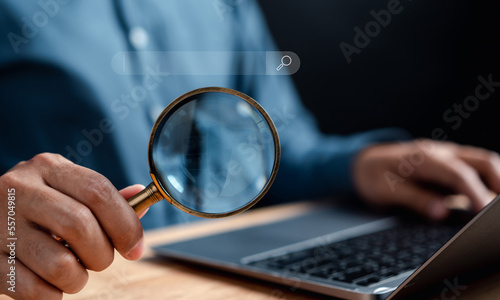 Businessman use magnifying glass Search On Virtual Screen Data Search Technology Search Engine Optimization. Man use computer to Searching for information. Using Search Console for data.
