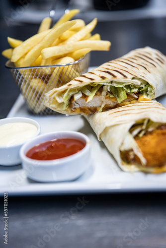 grilled chicken wrap on a plate with fries and sauce