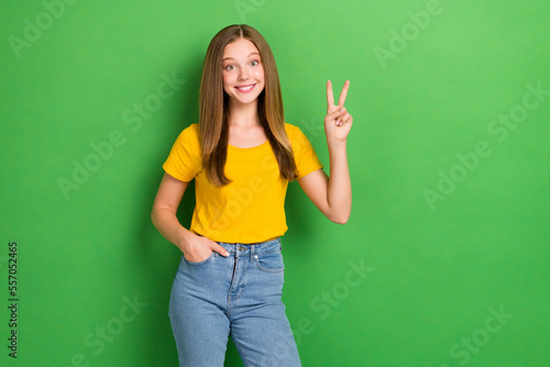 Photo of youngster teen age girl brown long beautiful hair toothy beaming smile showing v-sign friendly symbol isolated on green color background