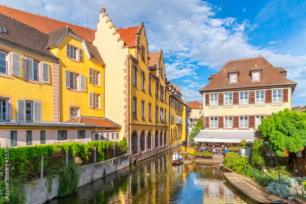 Colorful half timbered buildings and waterfront cafes on the Lauch River in the historic medieval Little Venice district of Colmar, France, in the Alsace region.