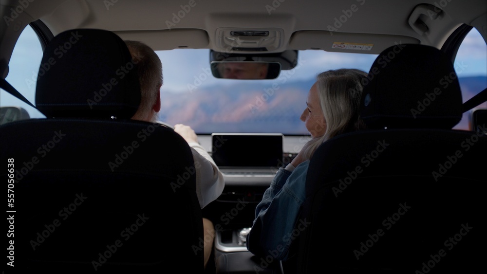 Back view of beautiful 60s mature senior grey haired Caucasian couple riding in a car, traveling together Back view of beautiful 60s mature senior grey haired Caucasian couple riding in a car, traveling together