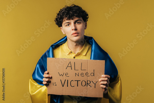 Ukrainian man with cardboard All we need is victory on yellow background. Ukraine will win war. Democracy, liberty, demonstration, russian aggresion concept photo