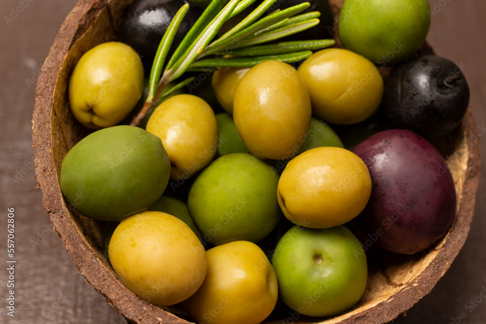 Multi-colored olives and a sprig of rosemary in coconut shell Multi-colored olives and a sprig of rosemary in coconut shell