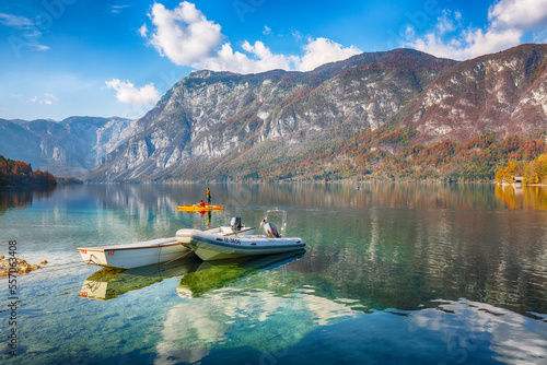 Amazing view of Bohinj Lake with boats during autumn .