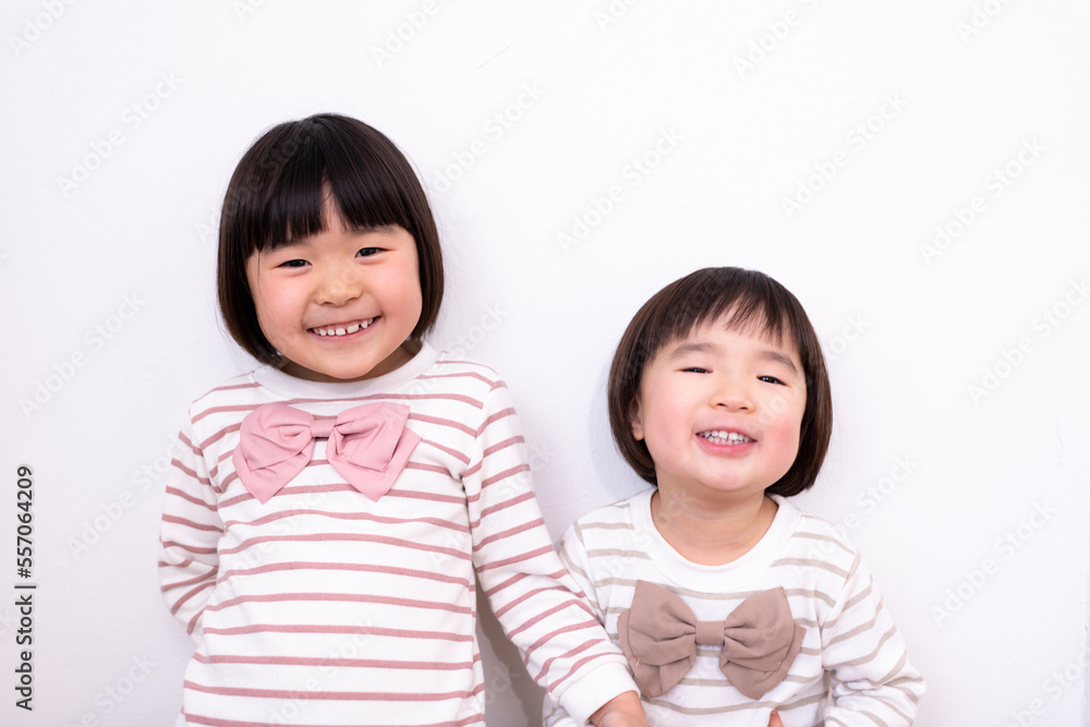 白い壁の前で笑っている姉妹 白い壁の前で笑っている姉妹