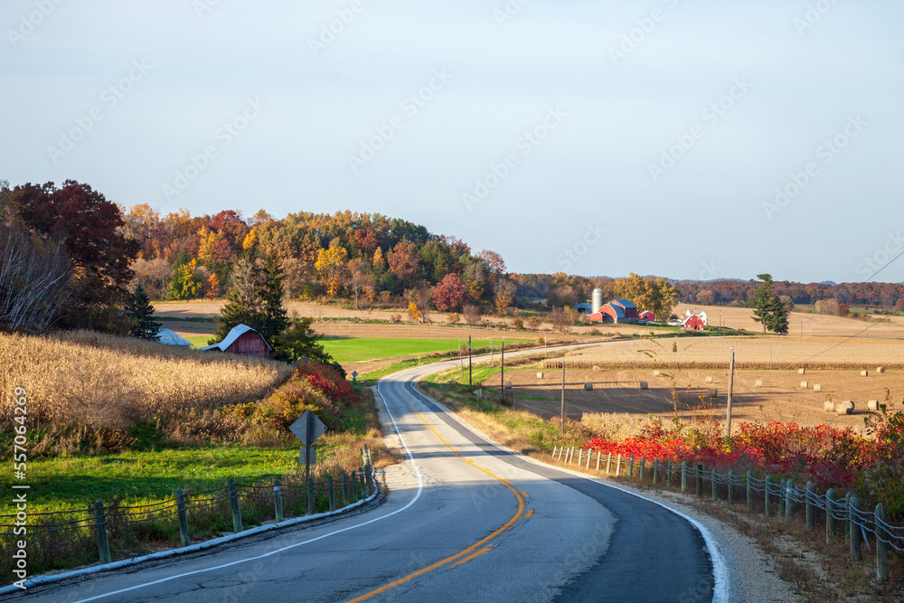Curving road and farms in Wisconsin on a sunny autumn evening