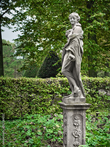 Stone statue on a pedestal of a woman facing you in the forest