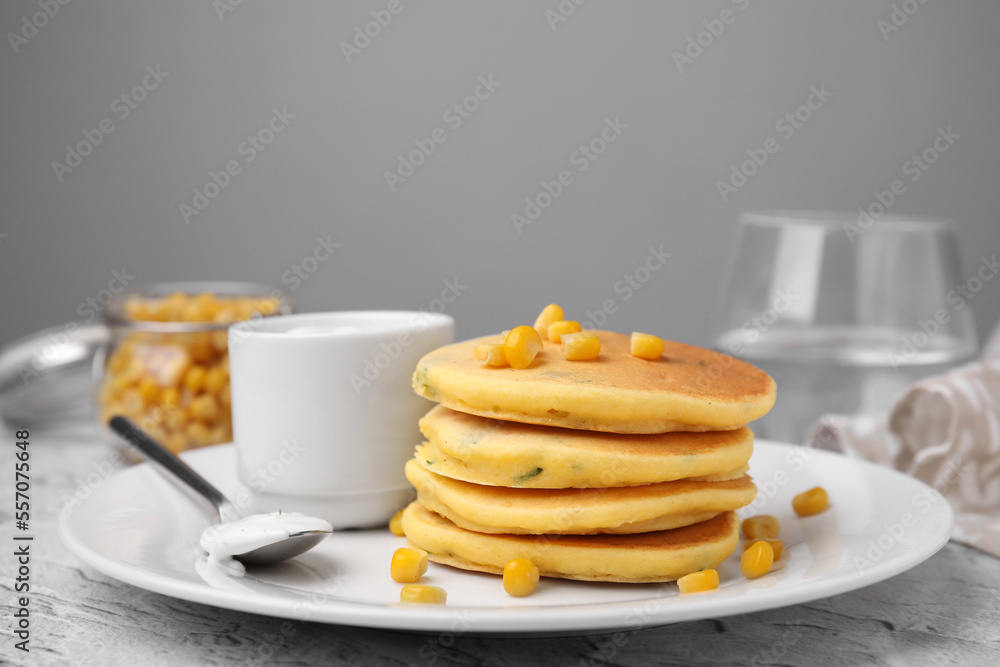 Tasty corn pancakes with sweet kernels and sauce served on grey table, closeup Tasty corn pancakes with sweet kernels and sauce served on grey table, closeup