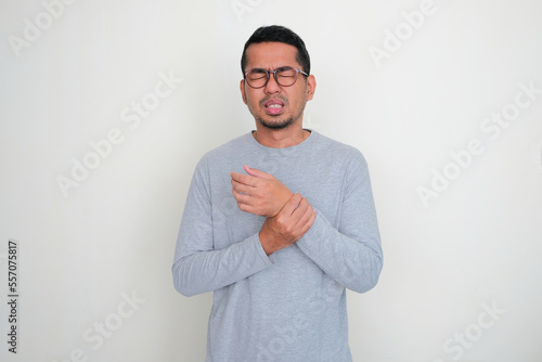 Adult Asian man touching his left hand wrist with in pain expression photo