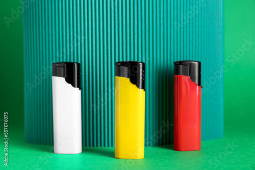 Stylish small pocket lighters and corrugated fiberboard on green background