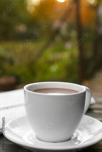 White cup with coffee and newspaper on table, closeup. Morning ritual