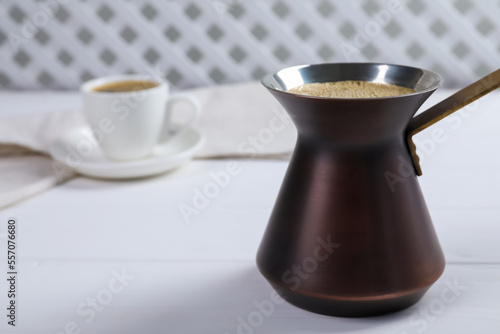 Turkish coffee pot with hot drink on white wooden table, space for text