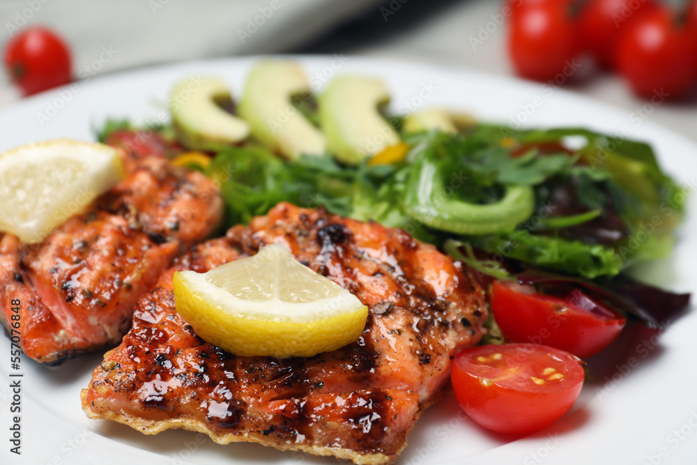 Tasty grilled salmon with lemon and tomatoes in plate, closeup Tasty grilled salmon with lemon and tomatoes in plate, closeup