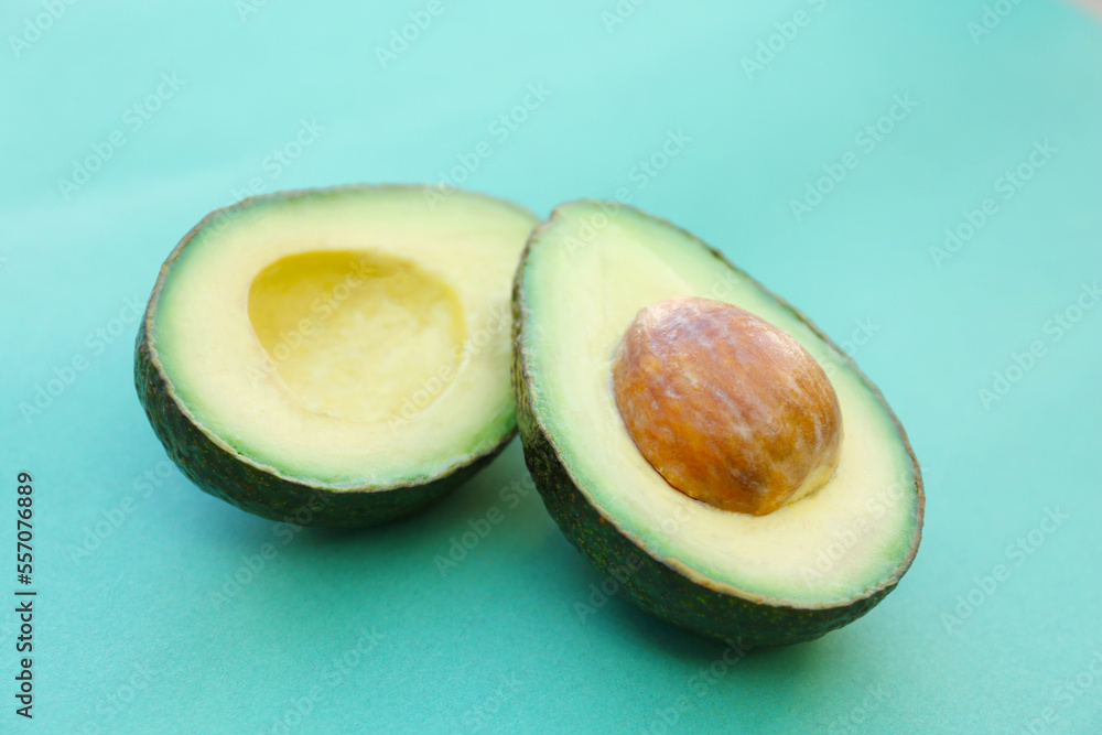 Tasty cut avocado on turquoise background, closeup