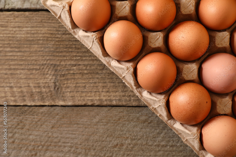 Fresh raw chicken eggs in carton on wooden table, top view. Space for text Fresh raw chicken eggs in carton on wooden table, top view. Space for text