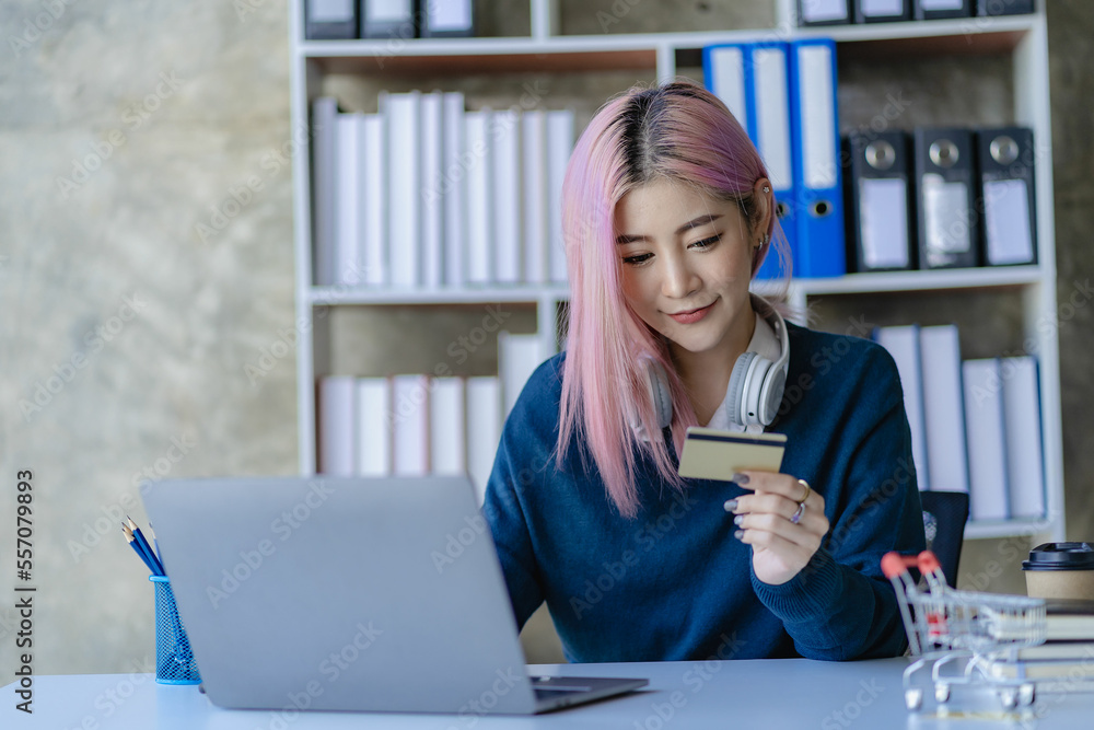 Asian woman holding credit card and using laptop computer for online shopping at home online shopping, e-commerce, internet banking, Asian woman holding credit card and using laptop computer for online shopping at home online shopping, e-commerce, internet banking,