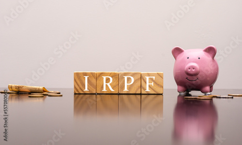 As iniciais IRPF de Imposto de Renda da Pessoa Física no Brasil escritas em cubos de madeira com um cofrinho na composição. Economia brasileira e finanças. photo