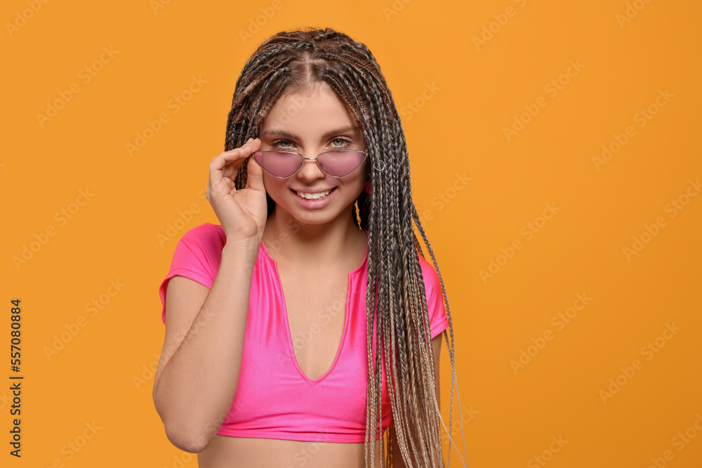 Beautiful woman with long african braids on yellow background, space for text