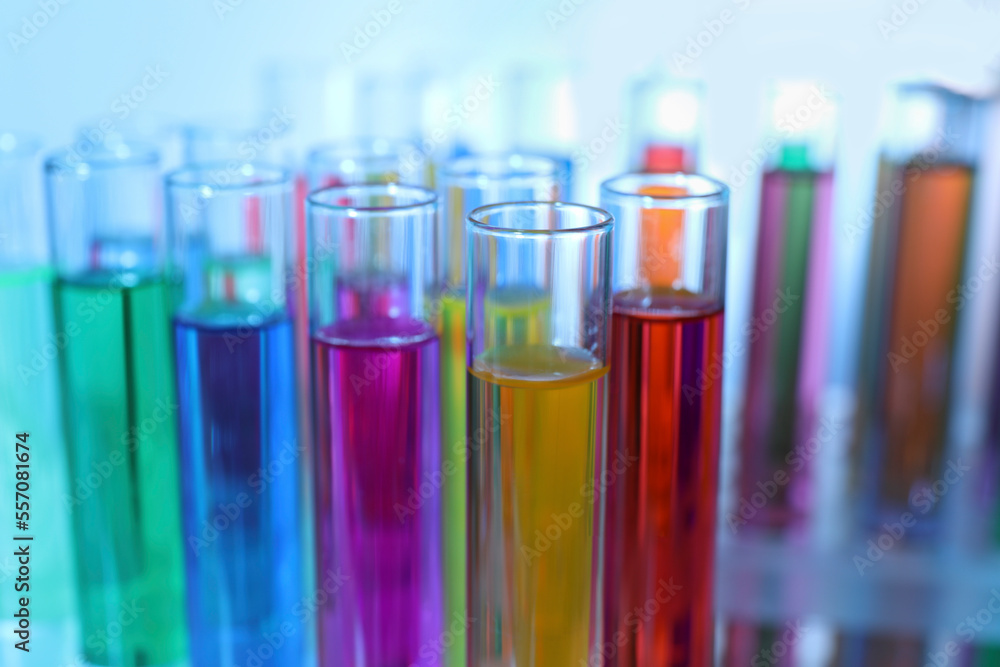 Many test tubes with colorful liquids on blurred background, closeup Many test tubes with colorful liquids on blurred background, closeup