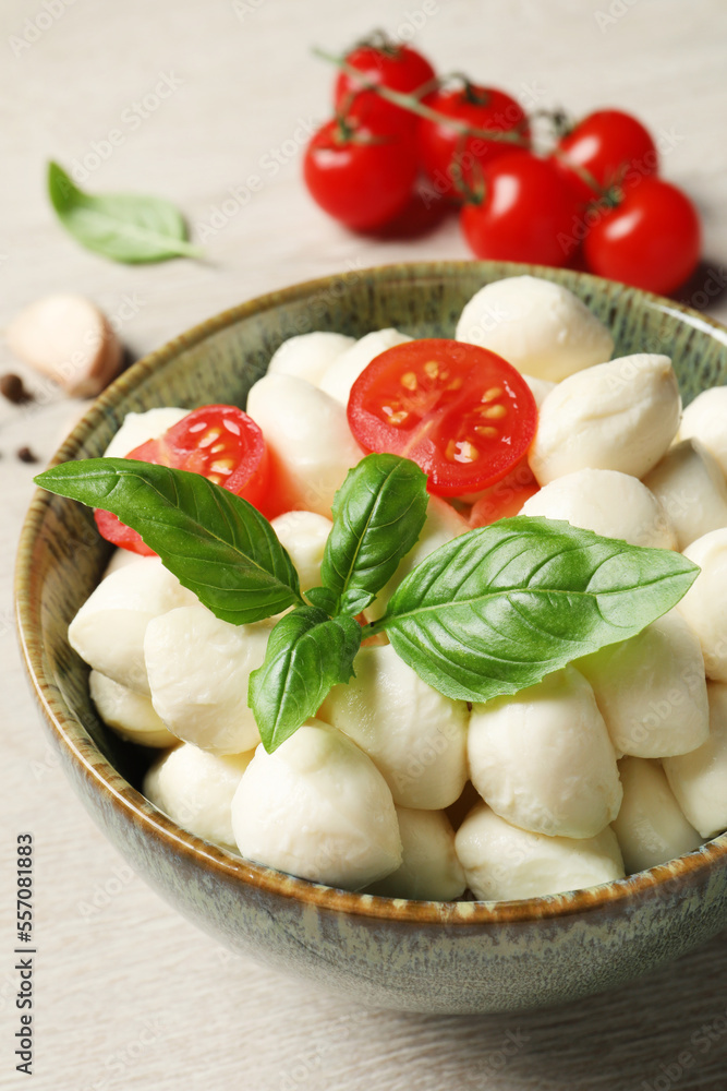 Delicious mozzarella balls, tomatoes and basil leaves in bowl on white wooden table, closeup Delicious mozzarella balls, tomatoes and basil leaves in bowl on white wooden table, closeup
